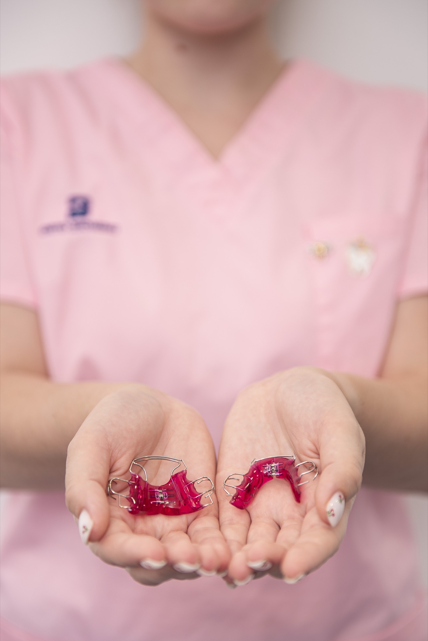 Aparaty ortodontyczne PinkLab trzymane w dłoniach